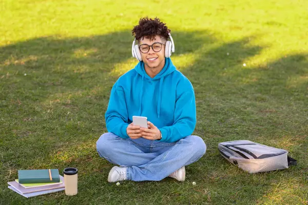 Estudiante Negro Sonriente Que Usa Auriculares Involucra Con Teléfono Móvil — Foto de Stock