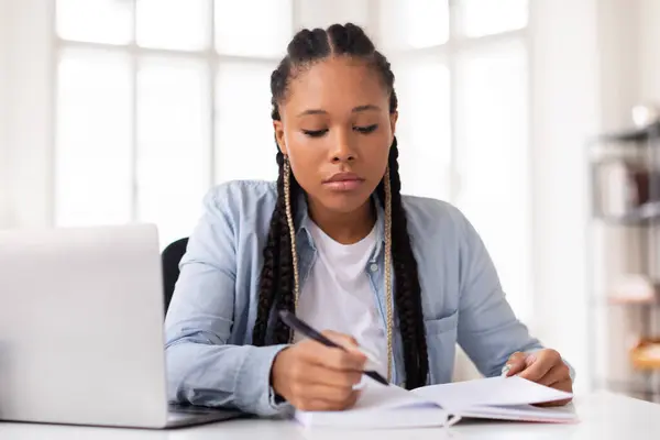 Mujer Joven Enfocada Escribiendo Intensamente Cuaderno Con Ordenador Portátil Abierto — Foto de Stock