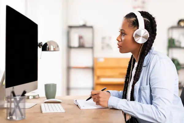 Kulaklıklı Siyah Bayan Öğrenci Masasında Dikkatle Çalışıyor Bilgisayar Ekranına Bakarken — Stok fotoğraf