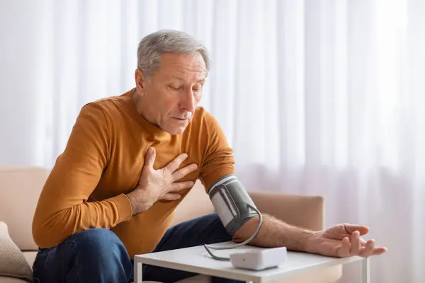 Älterer Mann Der Sich Hause Unwohl Fühlt Blutdruckkontrolle Mit Oberarmmonitor — Stockfoto
