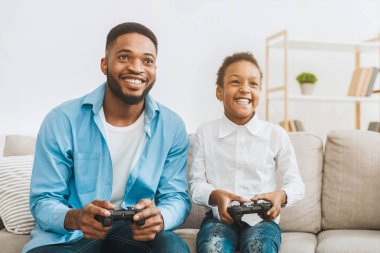 Mutlu afro babalar şirin kızıyla video oyunu oynuyorlar, evde joysticklerle oynuyorlar, bedava yer var.