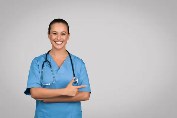 Щаслива Жінка Лікар Або Медсестра Блакитній Формі Вказує Осторонь Просторі — стокове фото
