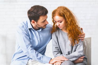 Rehabilitasyondaki psikologla görüşürken üzgün karısını teselli eden şefkatli bir koca.