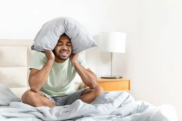 忧心忡忡的疲倦的非洲裔美国人 身穿睡衣 闭着眼睛坐在床上 头戴枕头 患有严重偏头痛 复制空间 — 图库照片