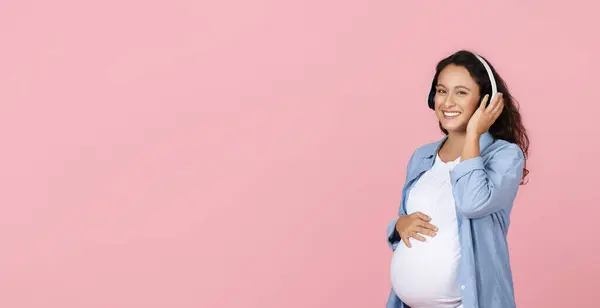 Беременная Женщина Слушает Музыку Наушниках Розовом Фоне Молодая Будущая Леди — стоковое фото