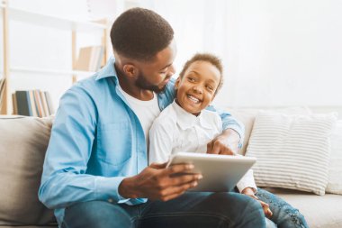 Afro baba ve kızı tablet kullanıyor, internetten kıyafet ve oyuncak sipariş ediyor, boş alan