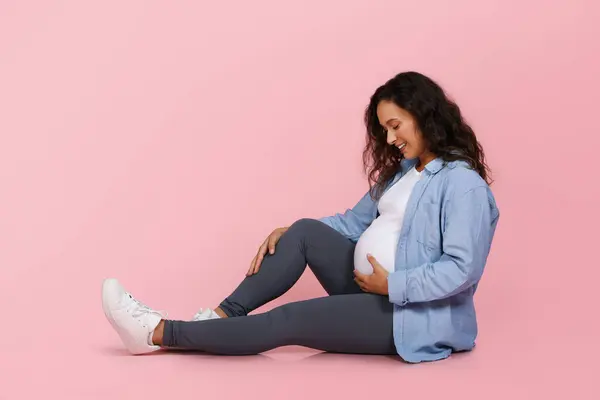 Счастливая Молодая Беременная Женщина Сидящая Полу Изолированная Розовом Фоне Студии — стоковое фото