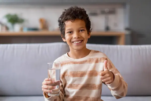 Smiling Little Black Boy Holding Glass Water Showing Thumb Camera — Stock Photo, Image