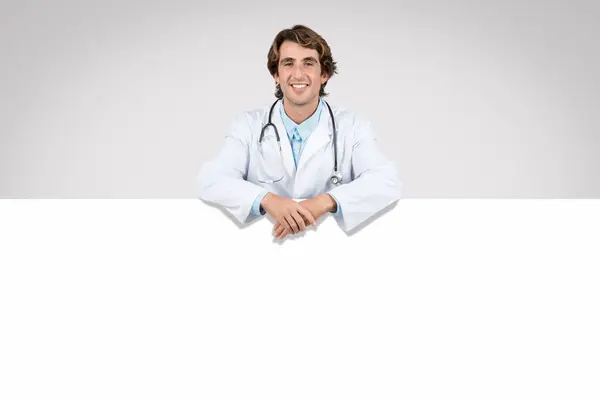 Young Male Doctor Stethoscope Leaning Blank White Banner Offering Engaging — Stock Photo, Image