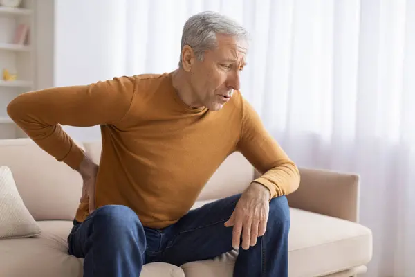 Unhappy Grandfather Sitting Couch Rubbing His Lower Back Feeling Pain — Stock Photo, Image