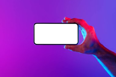 Erkek eli, cep telefonunun dokunmatik ekranının maketini gösteriyor. Mor mavi neon stüdyoda boş ekranlı telefonu tutuyor. Reklam uygulamaları ve modern teknoloji kavramları.