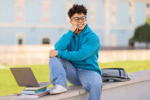 Eラーニング ワイヤレスイヤホンを持つハッピーブラジルの学生は オンライン講演に耳を傾け ラップトップとバックパック屋外に座って 大学のキャンパスパークでオンラインで学び 笑顔を見つめています — ストック写真