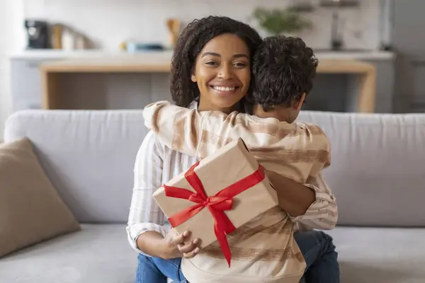 Happy Black Mother Embracing Her Little Son Holding Wrapped Gift — Stock Photo, Image
