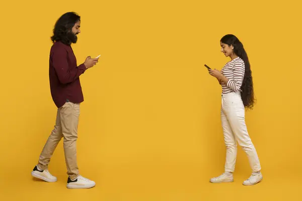 彼らの背中がお互いに向き合って 男性と女性は彼らの携帯電話にテキストで囲まれ 現代のコミュニケーションの問題を示しています — ストック写真