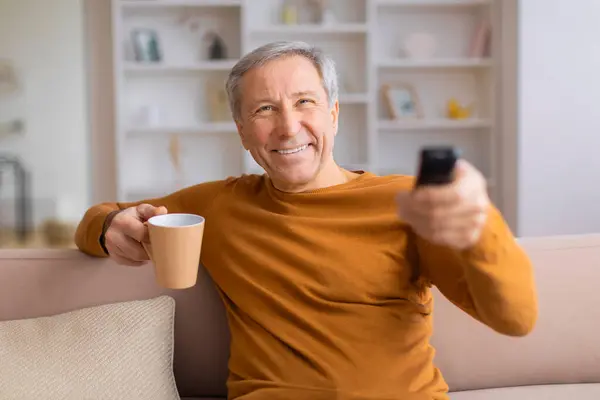 Starší Muž Neformálním Obleku Drží Hrnek Kávu Ovladač Televize Usmívá — Stock fotografie
