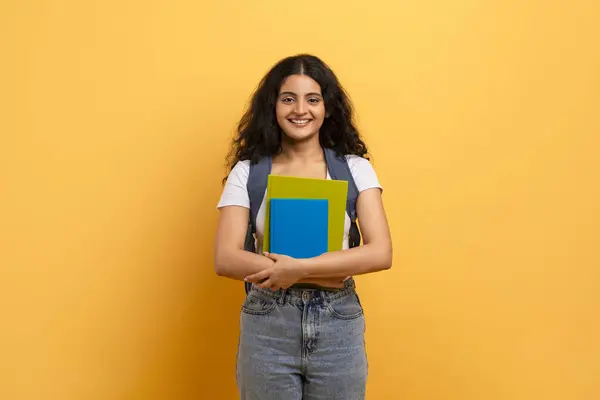 Confident Student Holding Blue Notebooks Yellow Background Symbolizing Learning Education — Stock Photo, Image