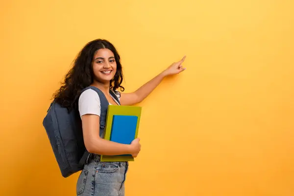 Smiling Student Backpack Pointing Sideways Yellow Backdrop Evoking Choice Direction — Stock Photo, Image