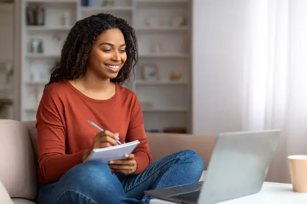 Lächelnde Junge Schwarze Frau Die Notizen Von Ihrem Laptop Aufschreibt — Stockfoto