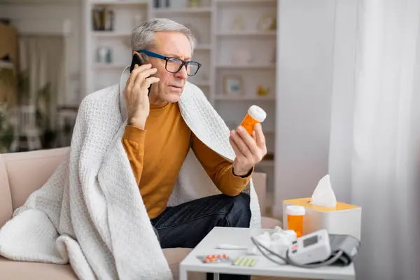 stock image Senior man in casual wear, holding medication bottle, with a blurred square board covering face