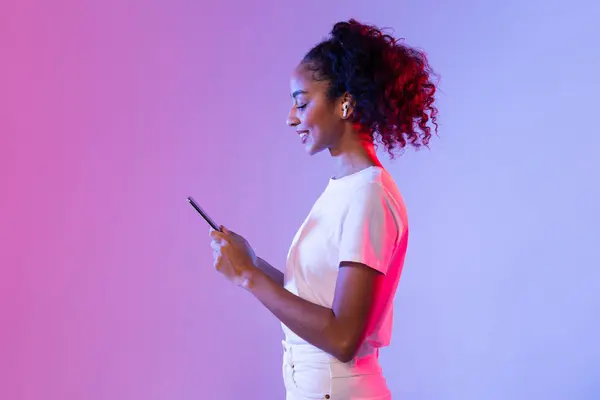 Akıllı Telefon Kablosuz Kulaklık Kullanan Kıvırcık Saçlı Neşeli Siyahi Bayanın — Stok fotoğraf