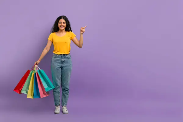 快乐的女人拿着购物袋向上看 带着紫色背景的微笑 — 图库照片