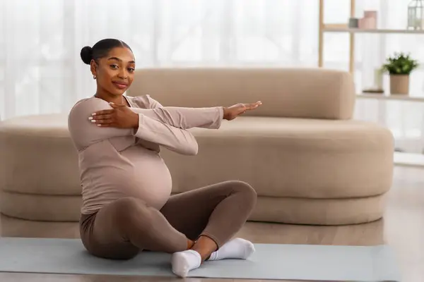 妊娠中の健康的なライフスタイル 自宅で体を伸ばす若い黒人女性を期待するポジティブな ヨガマットに座って 彼女のトレーニングを楽しんで コピースペース 未来の母親のためのスポーツ — ストック写真
