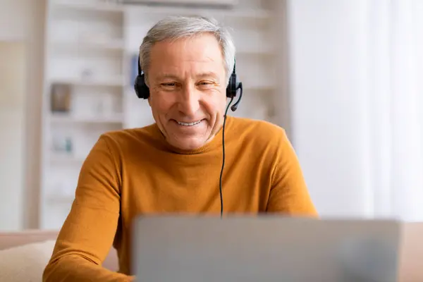 Cheerful Senior Man Wearing Headphones Looking His Laptop Screen Possibly — Stock Photo, Image