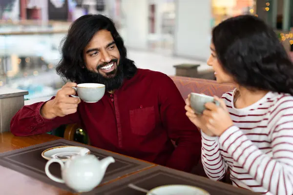 可爱亲切的印第安夫妇坐在城市咖啡馆的餐桌旁 喝着芬芳的咖啡 享受着彼此的陪伴 快乐的男人和他的女朋友在约会时进行了友好的交谈 — 图库照片