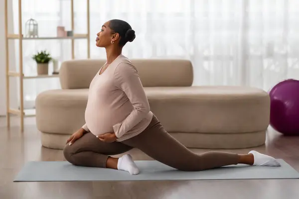 妊娠中のアフリカ系アメリカ人女性が 自宅で足のトレーニングを伸ばしています 期待する黒人女性は ヨガマット 健康的な妊娠コンセプト コピースペースでウォームアップエアロビクスエクササイズを行います — ストック写真