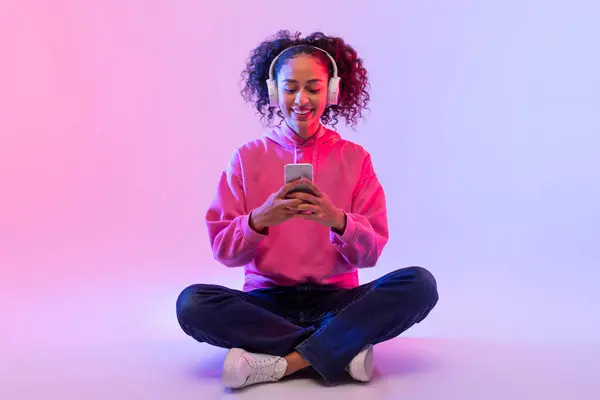 Χαλαρός Νεαρή Γυναίκα Ροζ Κουκούλα Χρησιμοποιώντας Ένα Smartphone Ενώ Κάθεται — Φωτογραφία Αρχείου