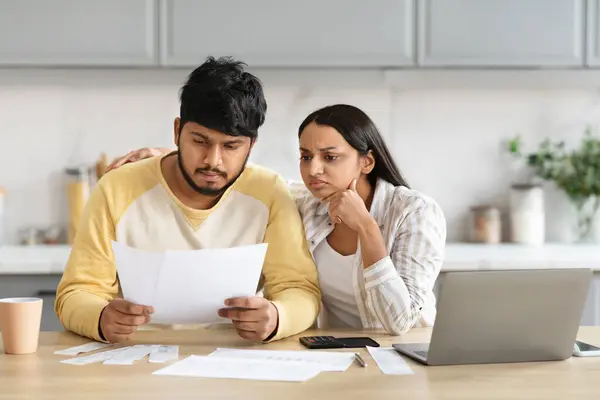 心烦意乱的印第安丈夫和妻子坐在电脑前的书桌前 阅读信件 检查账单 千禧年家庭都有债务 厨房的内部 复制的空间 — 图库照片