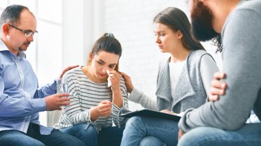 Terapi krizi. Rehabilitasyondaki grup toplantısında depresyondaki ağlayan kadını sakinleştiren insanları anlamak, sakinleşmesi için ona bir bardak su vermek.