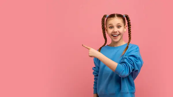 Expressive Young Girl Points Away While Looking Surprised Joyful Pink — Stock Photo, Image