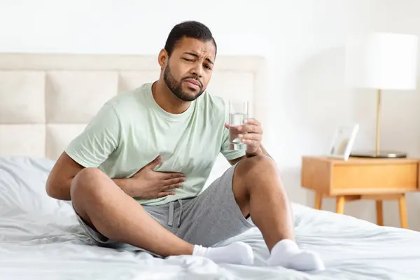 African American Man Distress Clutches His Stomach While Seated Bed — Stock Photo, Image