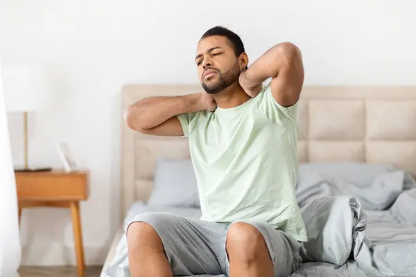 African American Man Grimaces Discomfort Touches His Neck Sitting Bed — Stock Photo, Image