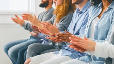 Atölye eğitimi konsepti. Çeşitli insanlar başarılı bir seminerden sonra alkışlıyor, çok ırklı grup sırada oturuyor ve el çırpıyor, yandan bakıyor