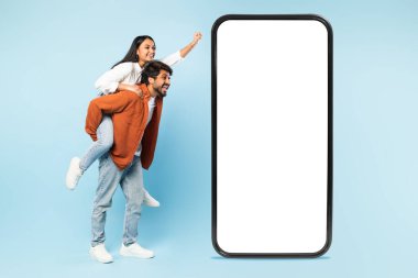 Gezici eğlence. Mutlu Hintli çift, büyük cep telefonlarının yanında eğleniyor. Beyaz ekranları var, kadınları sırtında taşıyorlar. Reklam teklifleri yapıyorlar, mavi arka plan, kolaj.
