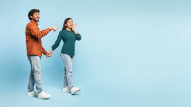 Neşeli, güzel Hintli çiftin el ele tutuşup yan yana baktıkları, reklam için boş bir alanı işaret ettikleri uzun bir sahne stüdyo, panorama