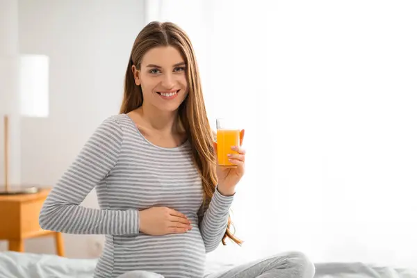 Lycklig Gravid Kvinna Randig Skjorta Håller Ett Glas Apelsinjuice Poserar — Stockfoto