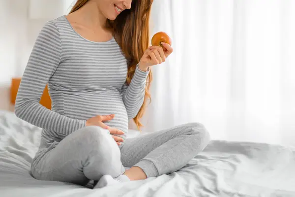 Hamile Bir Kadının Elmaya Bakıp Hamilelik Sırasındaki Sağlıklı Yiyecek Seçimlerini — Stok fotoğraf