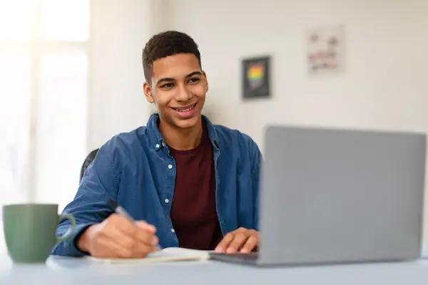 ハッピー アフリカ系アメリカ人のティーンエイジャー 青いシャツで勉強 灰色のラップトップコンピュータ ノートを取る 自宅の環境で学ぶことを楽しむ フリースペース — ストック写真