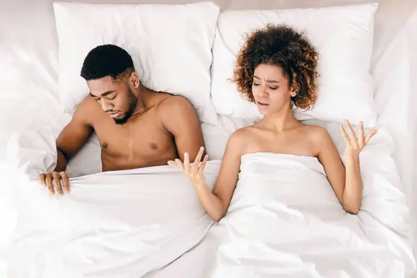 性问题 不安的黑人恋人躺在床上 女人不满意 悲伤的男人看着毯子下 顶视图 — 图库照片