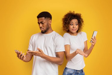 Bağlantı hatası. Siyah bin yıllık erkek ve kadın akıllı telefonlar, ordudan terhis edilen veya kırık cep telefonları ile rahatsız bakarak iletisinde kötü haber aldı