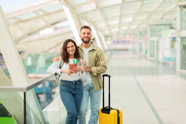 空港ターミナルでチケットを一緒に披露する陽気な若いカップルは 彼らの旅についての興奮を表現します — ストック写真