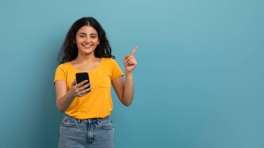 Akıllı telefon kullanan ve güzel bir gülümsemeyle solunu gösteren mutlu bir kadın.