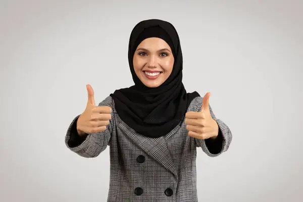 ハッピーでポジティブなプロの女性 ヒジャブとスタイリッシュなスーツ つの親指を与える 自信と承認を除外 灰色の背景で孤立 — ストック写真
