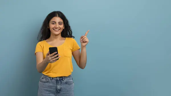 Conteúdo Mulher Usando Smartphone Apontando Para Esquerda Com Sorriso Agradável — Fotografia de Stock