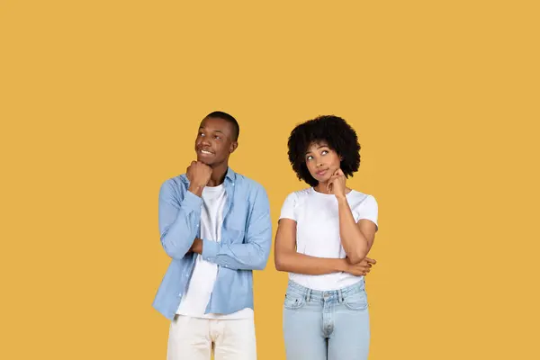 2人の若いアフリカ系アメリカ人の個人は マスタード黄色の背景に立って 決断やアイデアを考慮して 慎重な表現で手を傾けます スタジオ — ストック写真