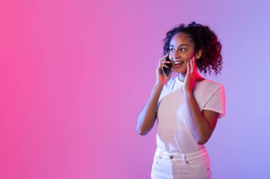 A young woman happily chatting on a smartphone with a vibrant pink and purple neon background clipart