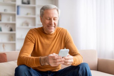 Neşeli, yaşlı, kır saçlı, akıllı telefon kullanan, web sörfü yapan, internetten haber okuyan, dijital dünyadan keyif alan, uzay kopyalayan yaşlı bir adam.